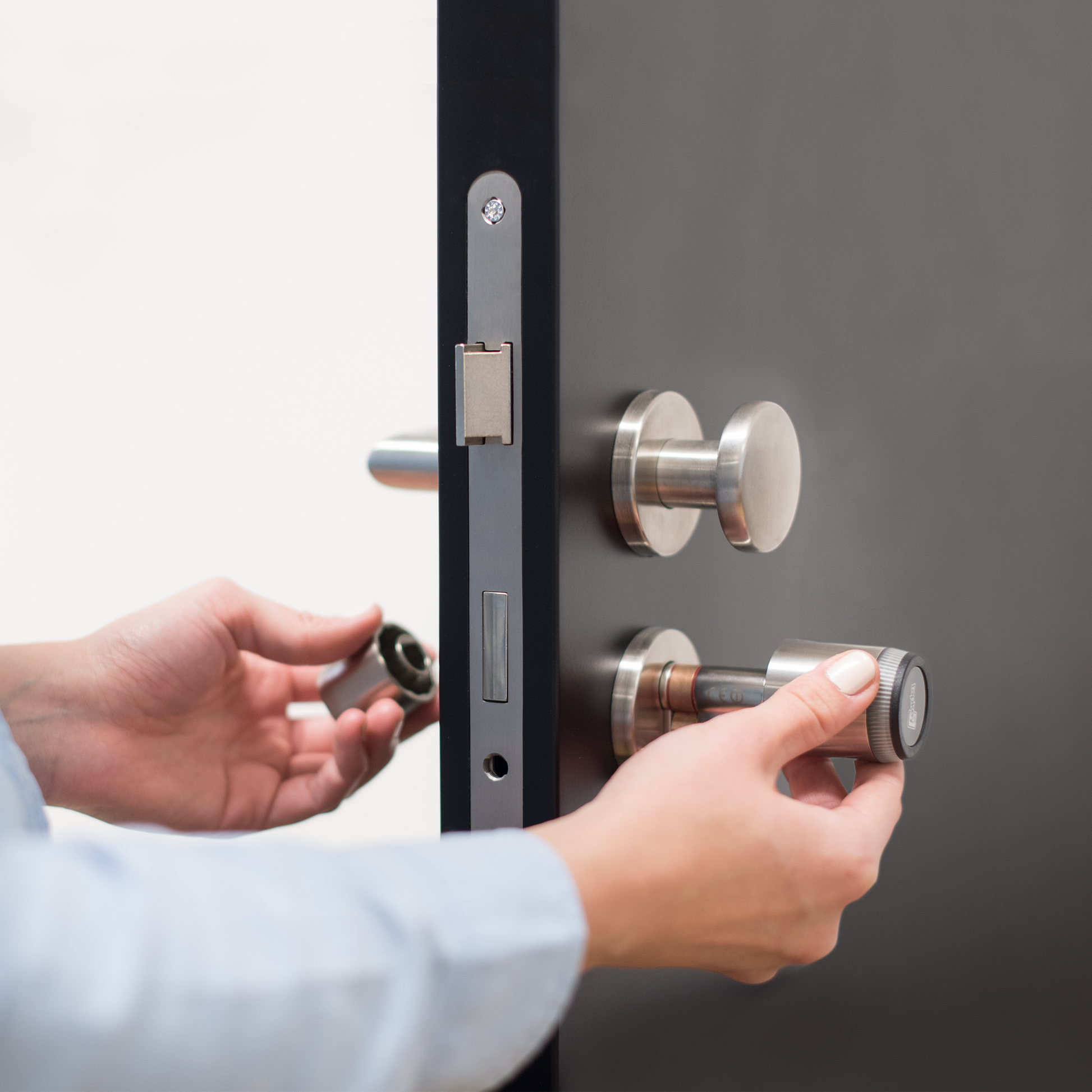 Someone installing a Tapkey Smart Lock into a door. | Jemand baut ein Tapkey Smart Lock in eine Tür ein.